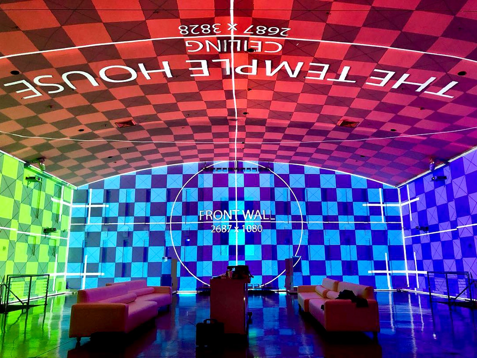 An immersive room with projection on the front wall and curved ceiling showing alignment grids
